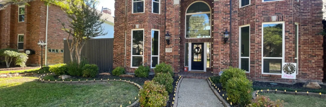 Brick house with arched entrance, landscaped front yard, and pathway