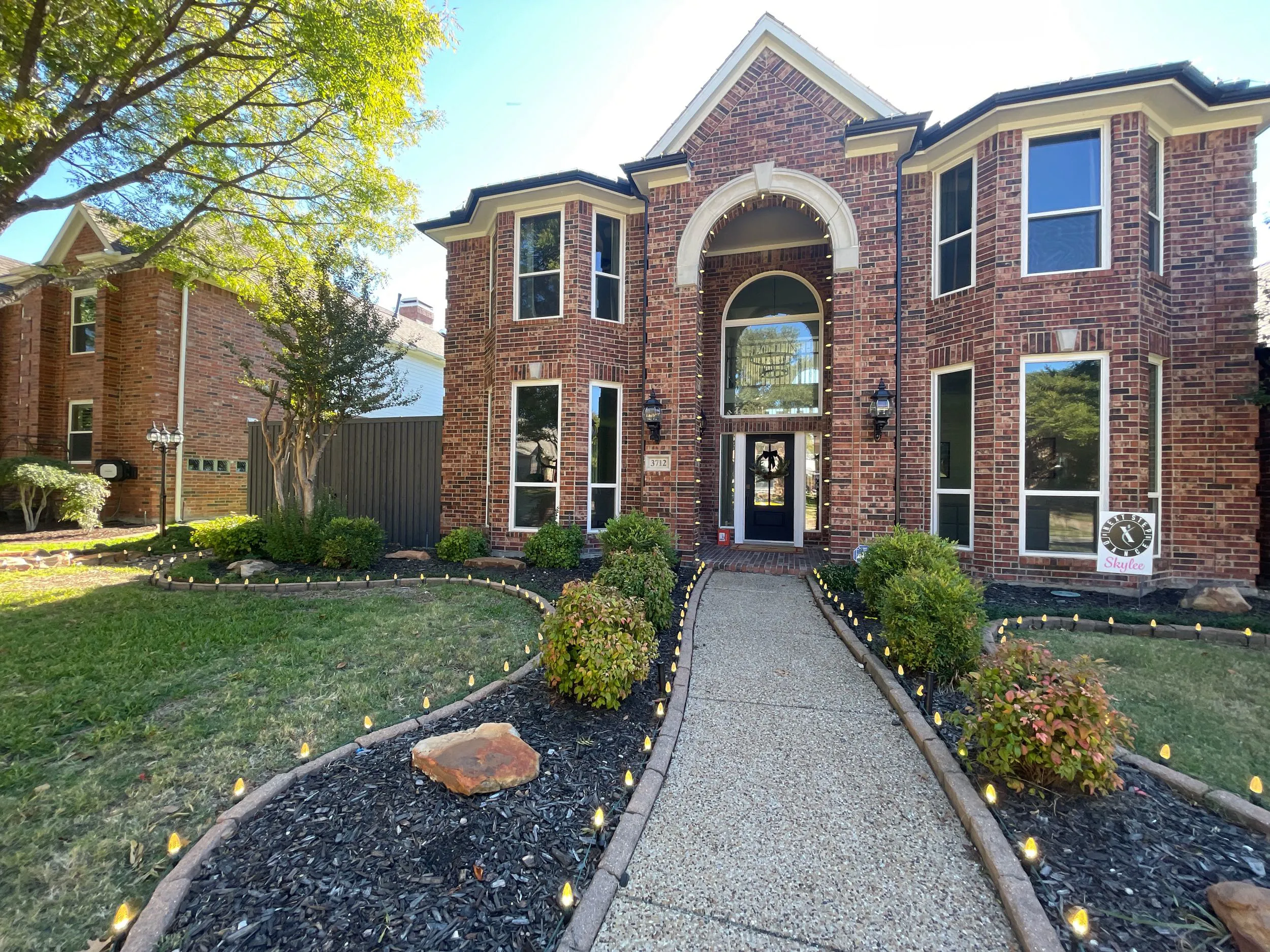 Brick house with arched entrance, landscaped front yard, and pathway