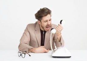 Man Wearing Brown Suit Jacket Mocking On White Telephone 1587014